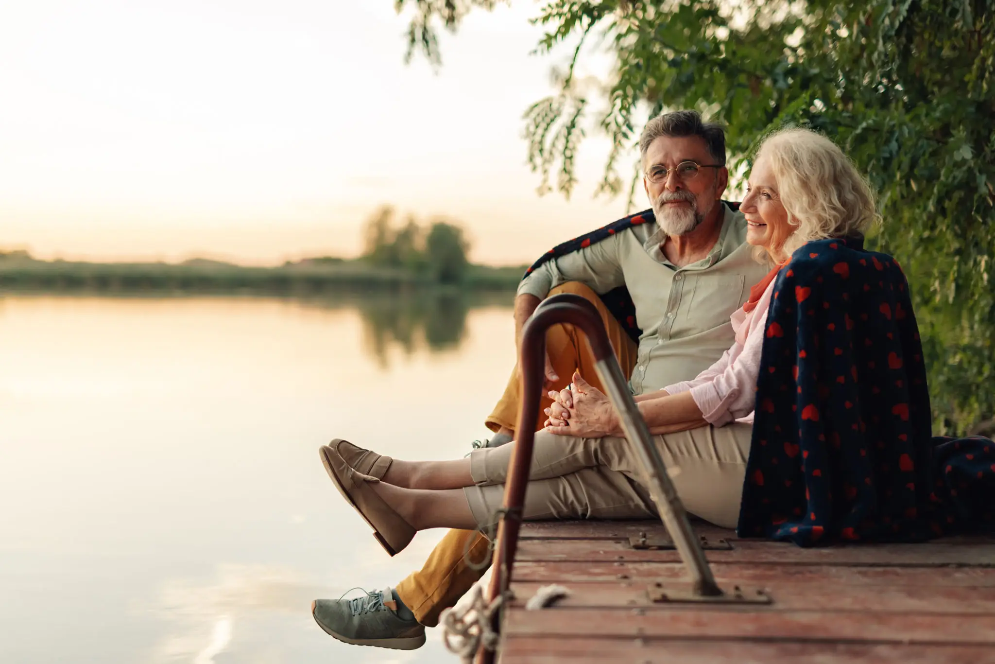 Elderly couple sitting on a lakeside dock.