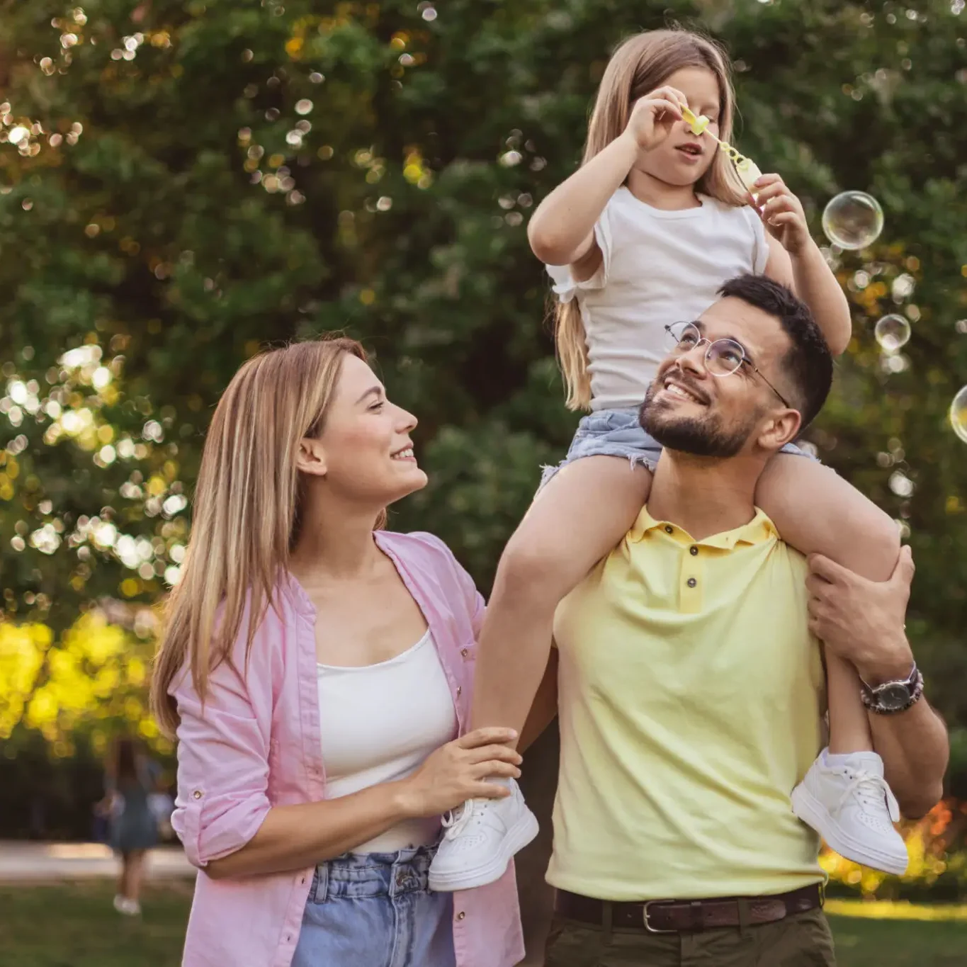 Family enjoying time blowing bubbles outdoors.